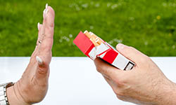 A hand rejects another hand holding an open pack of cigarettes